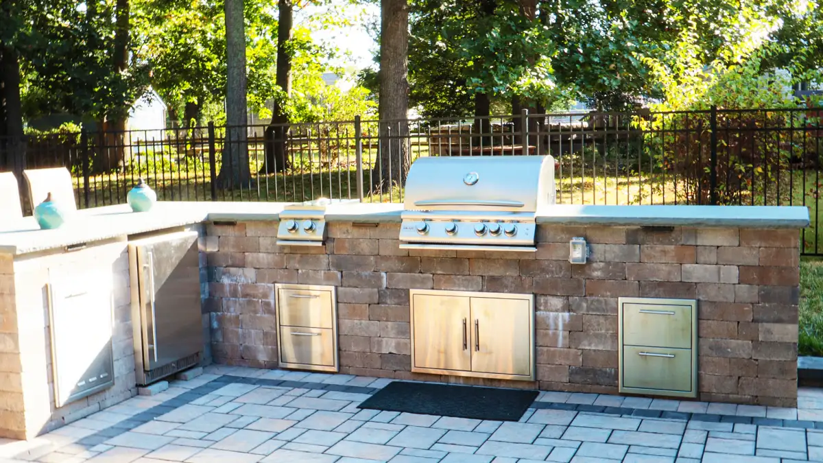 Paver patio with herringbone pattern and stone seat wall installed by Miller's Landscaping